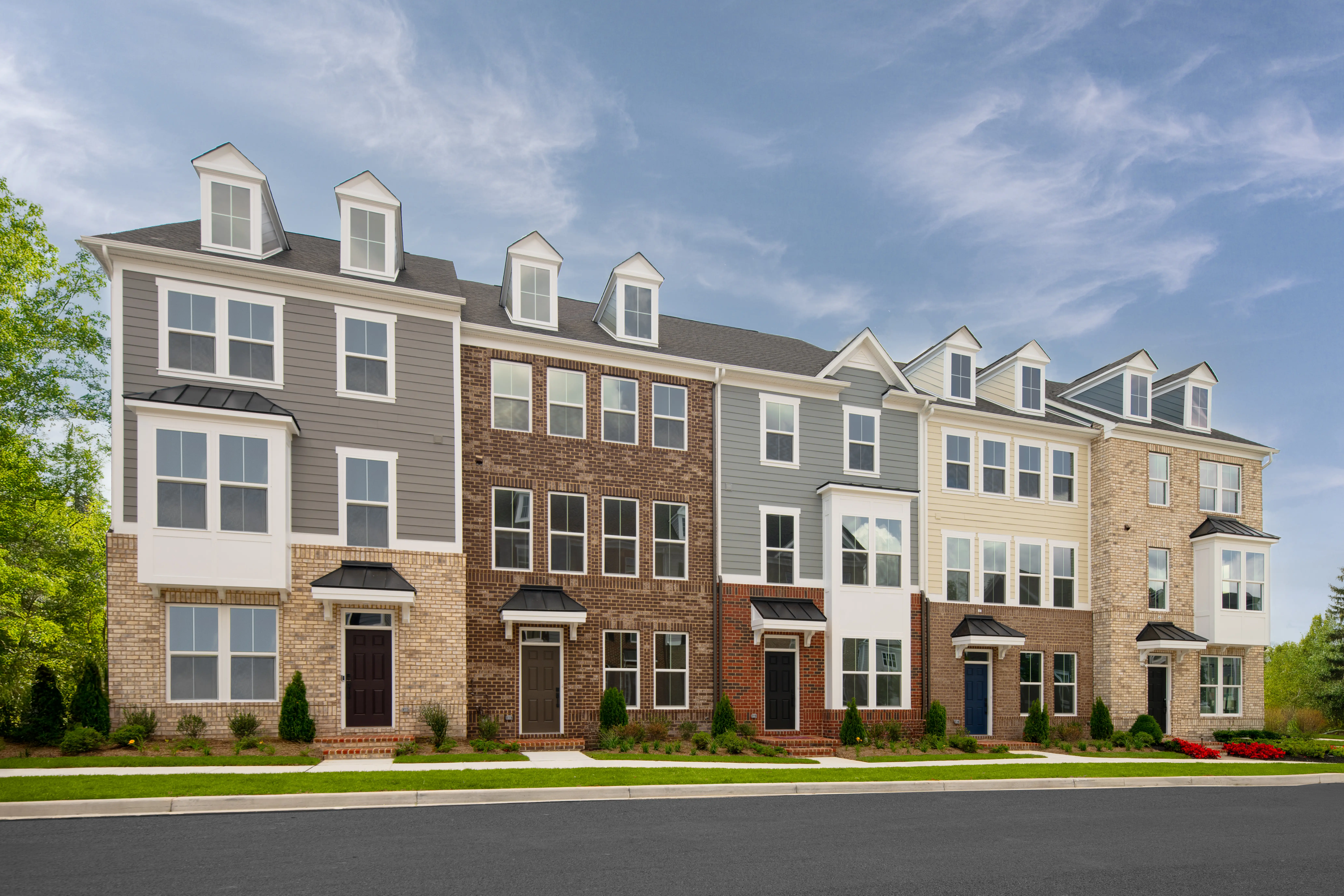 Exterior of a row of modern townhomes underneath a sunny sky at Greenleigh by NVHomes